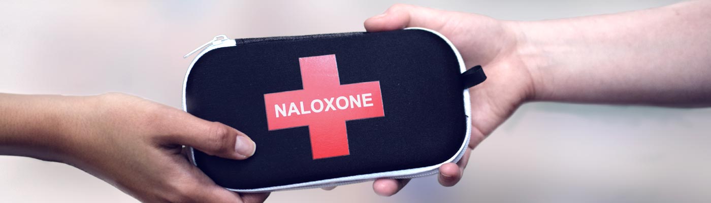 Two hands holding a naloxone kit