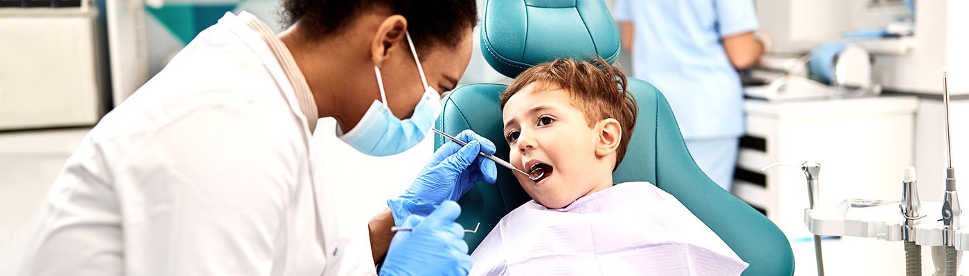  Dentiste vérifiant la bouche de l'enfant dans un fauteuil dentaire
