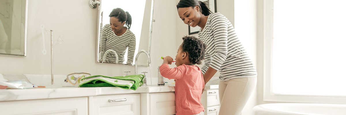 Adult watching child brush their teeth at the sink