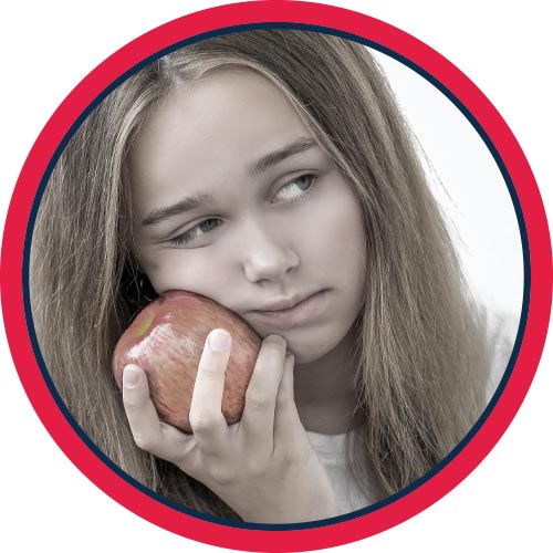 Child holding apple against outer cheek.