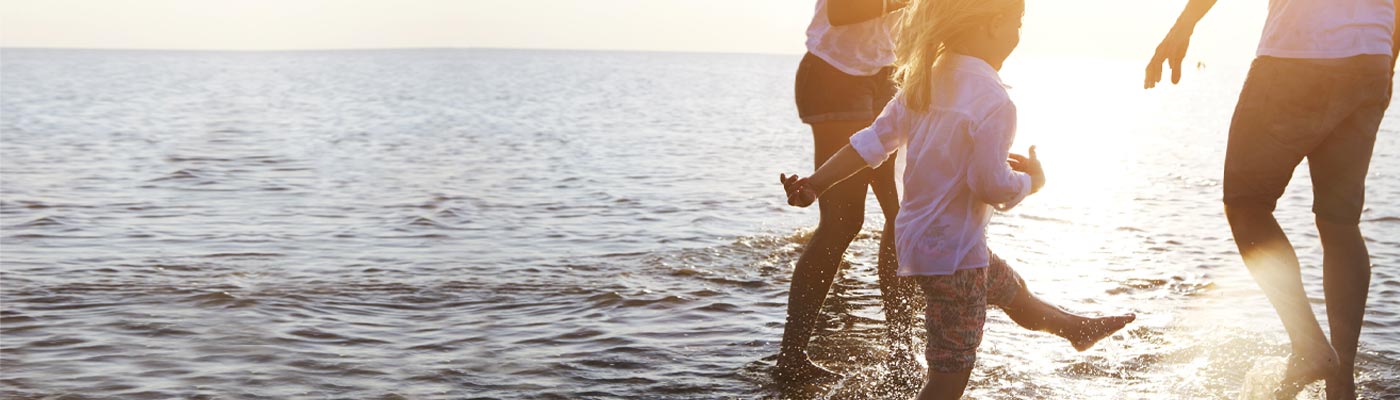 Two adults and one child walking in water