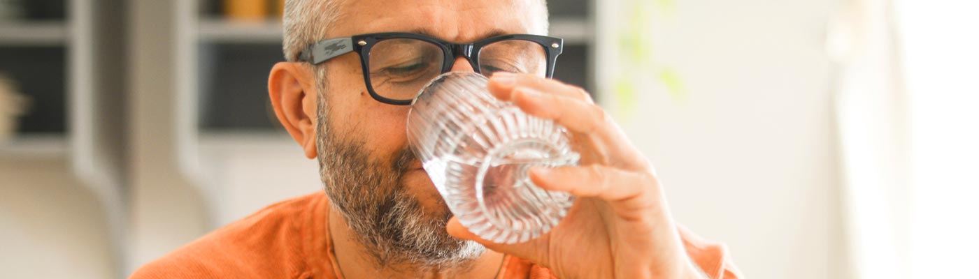 Adulte buvant de l'eau dans un verre