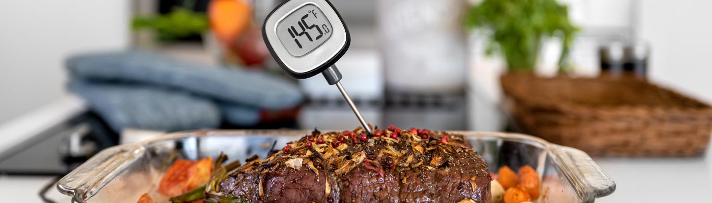 Meat thermometer with numbers 145 degrees fahrenheit inserted into cooked meat. 