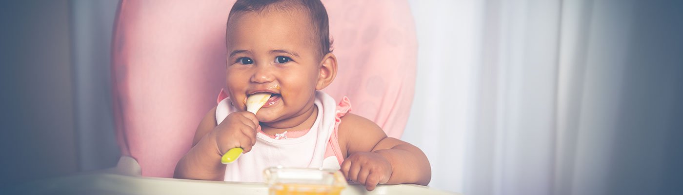 Baby sitting in highchair eating puree