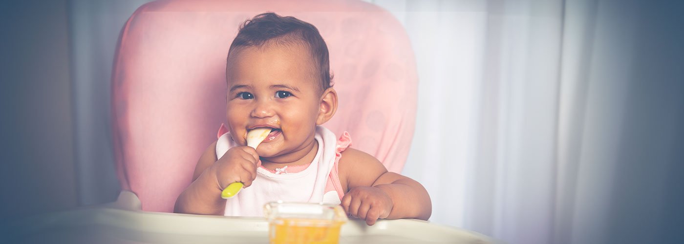 Baby sitting in highchair eating puree