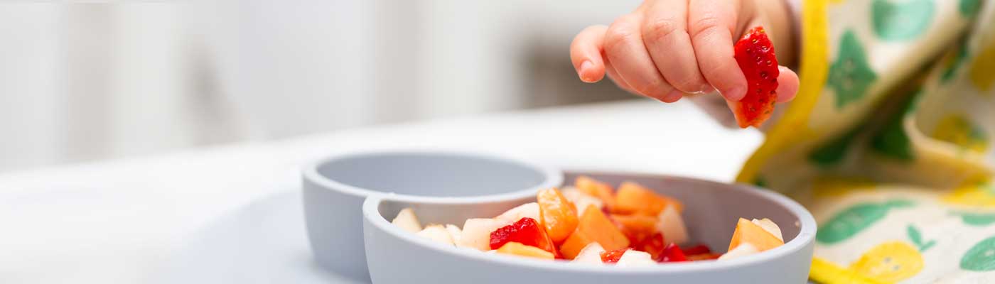 Baby holding a piece of strawberry