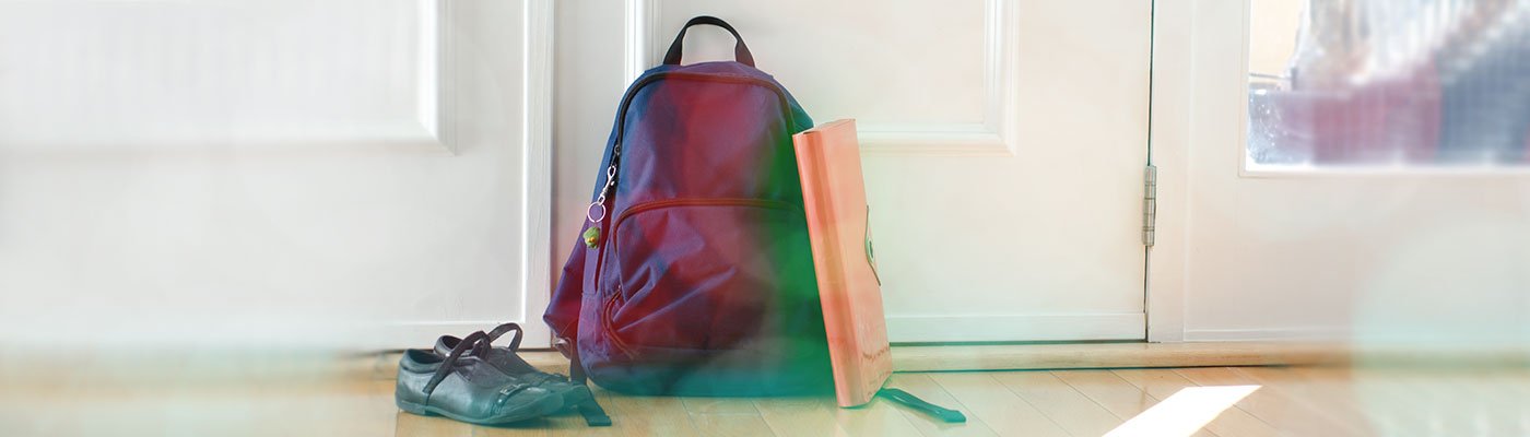 Backpack and shoes inside on floor in front of a door