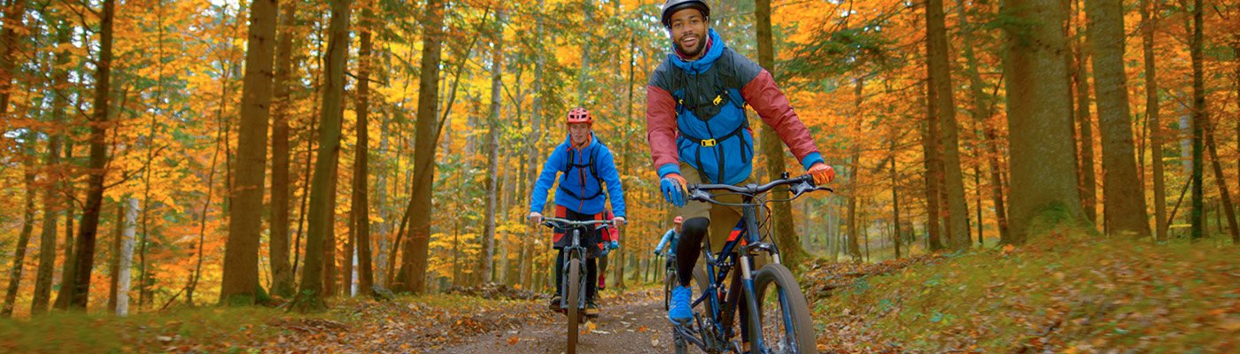 adults cycling through a wooded trail