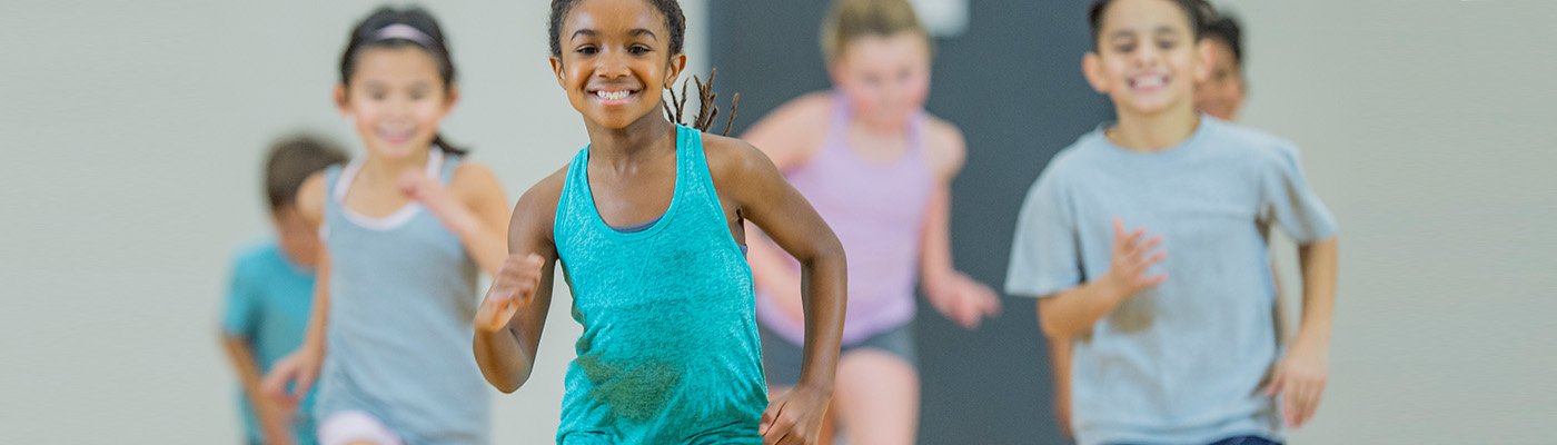 school aged children running in a gym