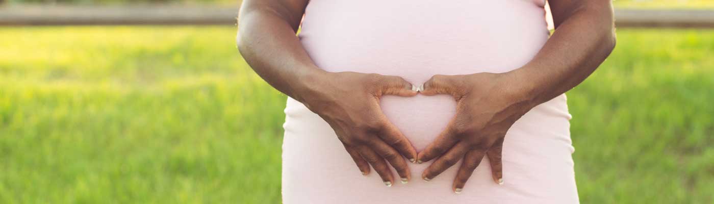 Person outside holding their hands over their stomach in a heart shape