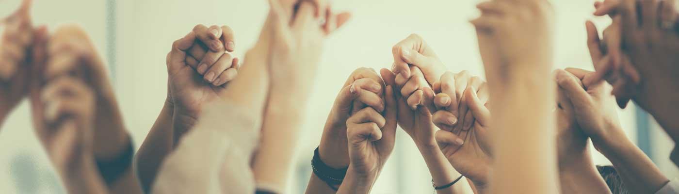 Close up of multiple hands being held and raised into the air