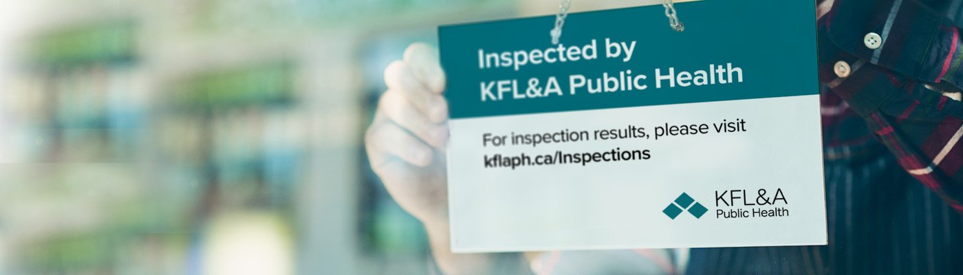 hands holding an inspected by KFLA Public Health sign