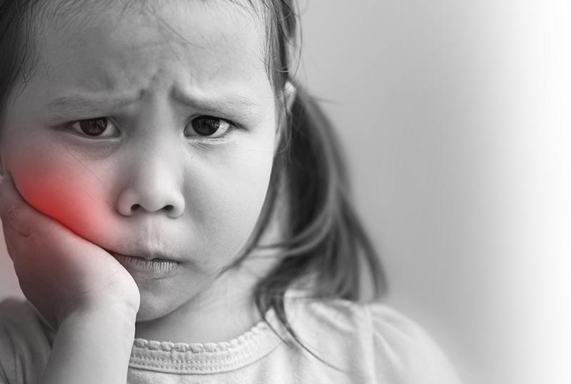 Child holding hand against cheek.